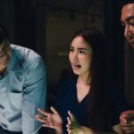 Three colleagues in discussion around a table in a darkened office at night